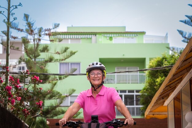 Senior mujer activa en bicicleta en la ciudad en su bicicleta eléctrica anciana atractiva mujer disfrutando de un estilo de vida saludable