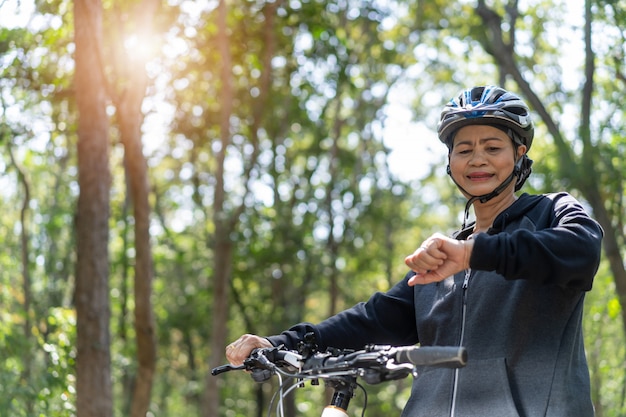 Senior mujer asiática en bicicleta en el parque