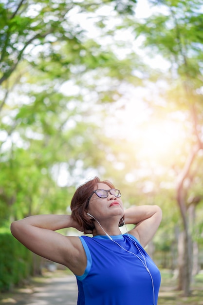 Senior mujer asiática relajada escuchando música en el parque