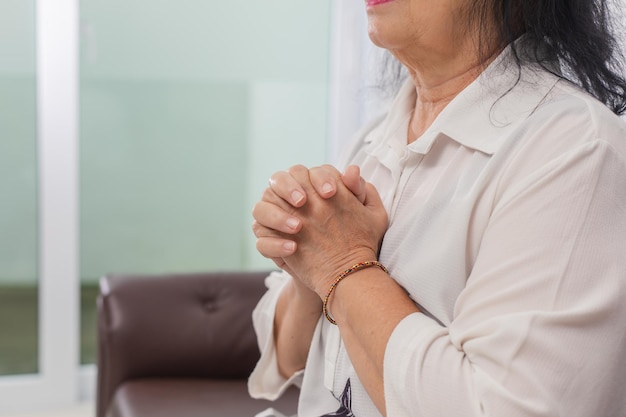Senior mujer asiática rezando a Dios en casa