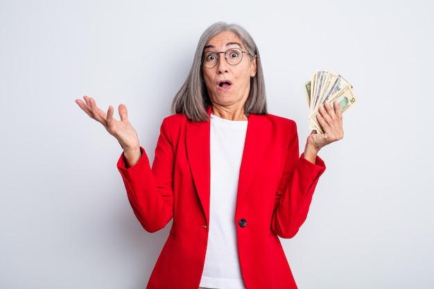 Senior mujer bonita sorprendida, conmocionada y asombrada con una sorpresa increíble. concepto de negocio y billetes