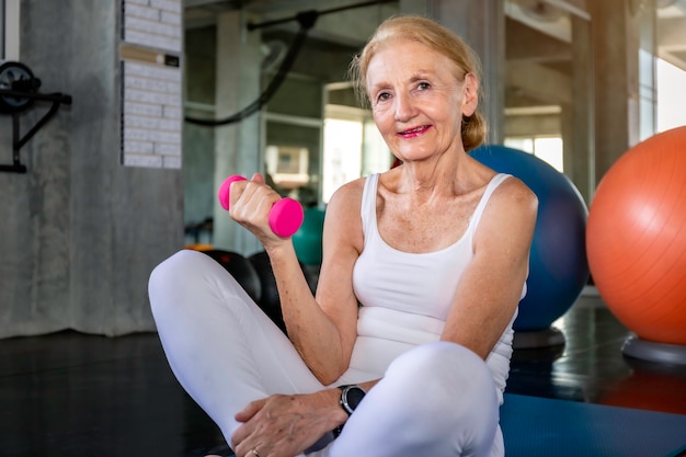 Foto senior mujer caucásica brazo de entrenamiento con mancuernas en el gimnasio.