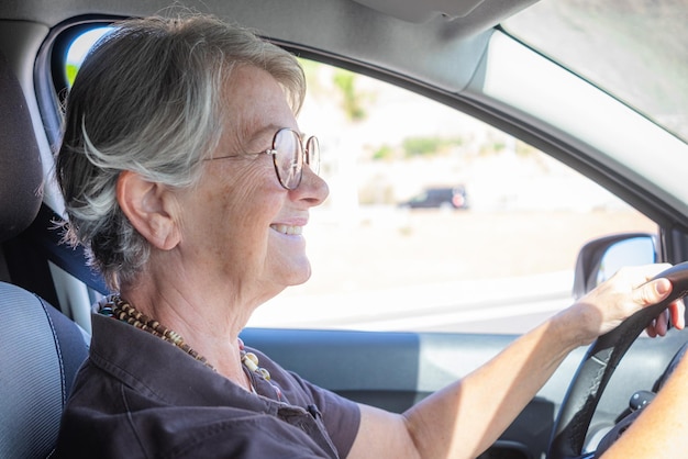 Senior mujer caucásica conduciendo el coche anciana segura de sí misma disfrutando de conducir y viajar