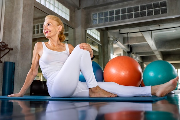 Senior mujer caucásica haciendo ejercicio de yoga en el gimnasio.