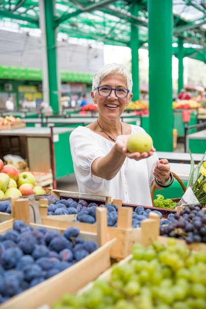 Senior mujer comprando manzanas en el mercado