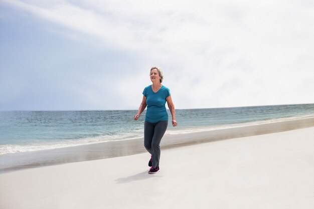 Senior mujer corriendo en la playa