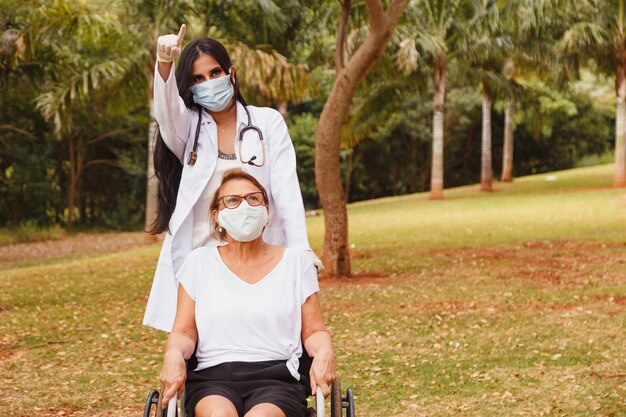 Senior mujer discapacitada con cuidador en el jardín del hogar de ancianos