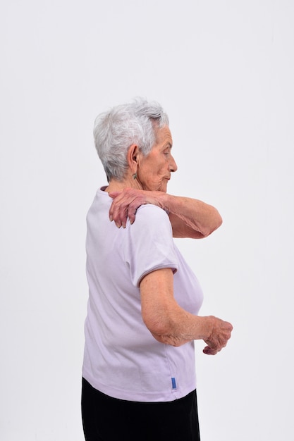 Foto senior mujer con dolor en el hombro sobre fondo blanco.