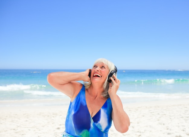 Senior mujer escuchando algo de música junto al mar