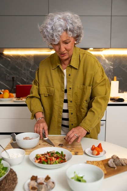 Senior mujer haciendo plato con higos en la cocina