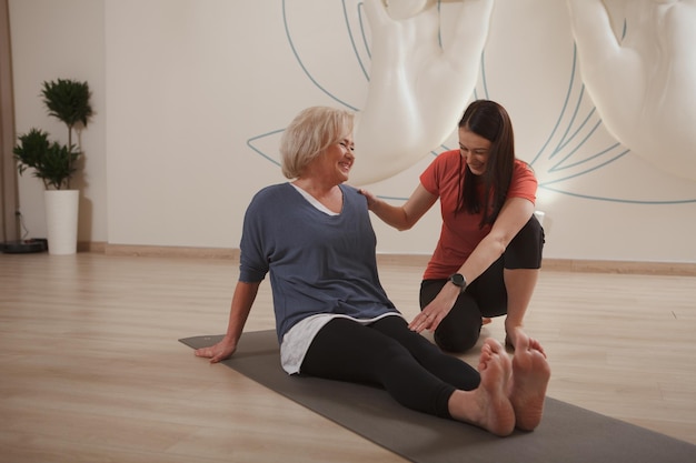 Senior mujer haciendo yoga con instructor profesional