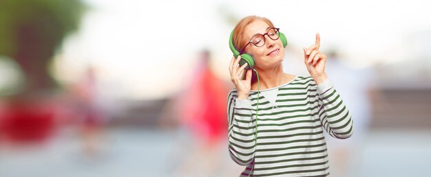 Senior mujer hermosa escuchar música con auriculares