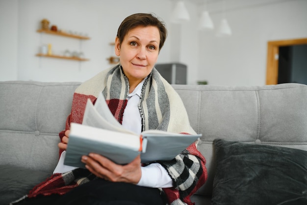 Senior mujer leyendo un libro en casa