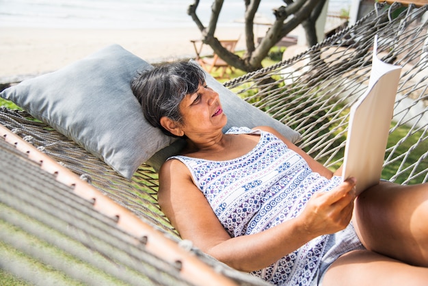Senior mujer leyendo una revista en una hamaca