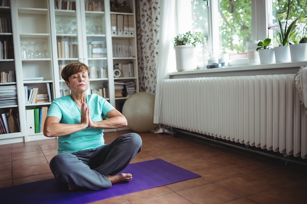 Senior mujer meditando en posición de oración