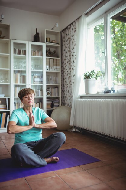 Senior mujer meditando en posición de oración