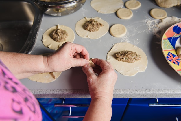 Senior mujer prepara khinkali.