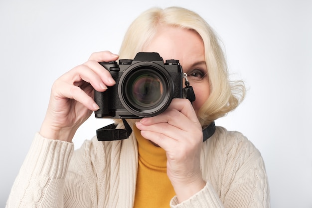 Senior mujer rubia tomando fotos con cámara