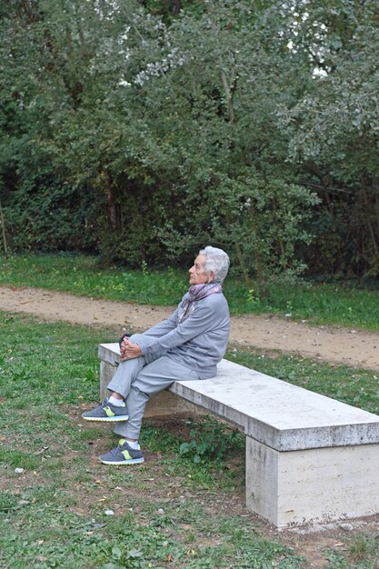 Senior mujer sentada sola en un banco en un parque