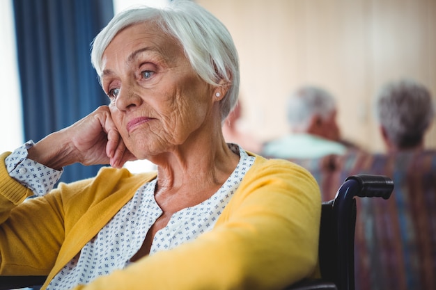 Senior mujer en silla de ruedas parece preocupada