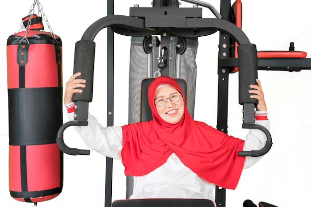 Senior mujer sonriendo a la cámara en la máquina de gimnasio