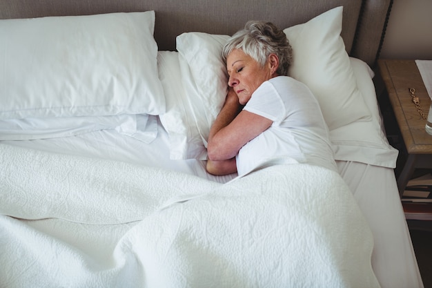 Sênior mulher dormindo na cama no quarto