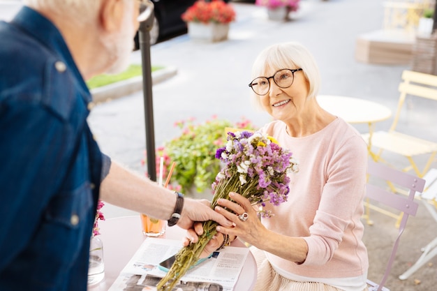 Sênior oferecendo flores para a esposa