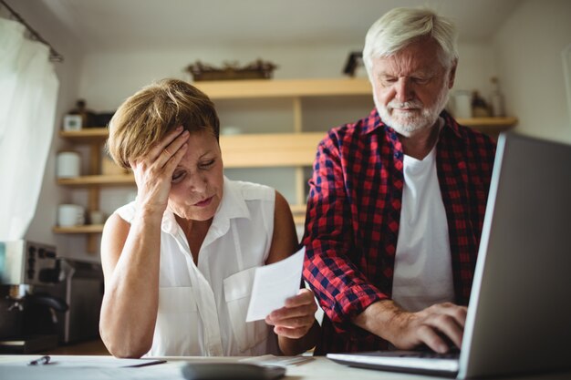 Senior par pagar facturas en línea en la computadora portátil