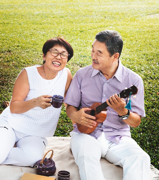 Senior pareja asiática tocando música en un parque