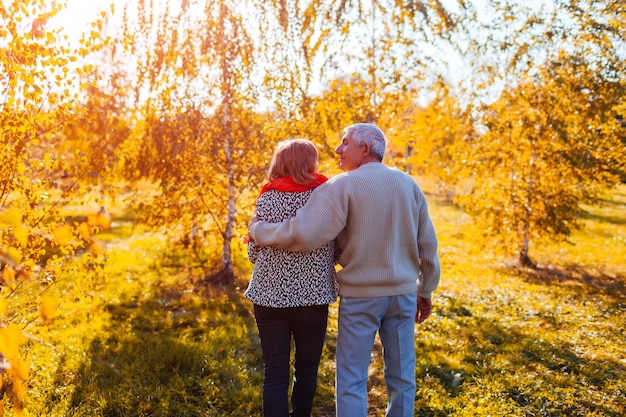 Senior pareja caminando en el bosque de otoño Hombre de mediana edad y mujer abrazando