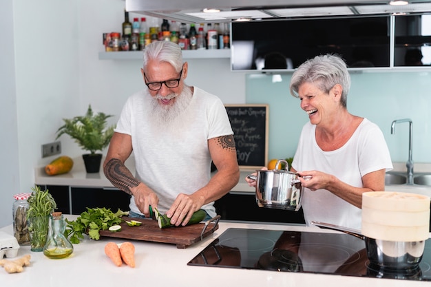 Senior pareja cocinando en casa mientras prepara el almuerzo vegetariano