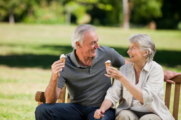 Senior pareja comiendo un helado en un banco