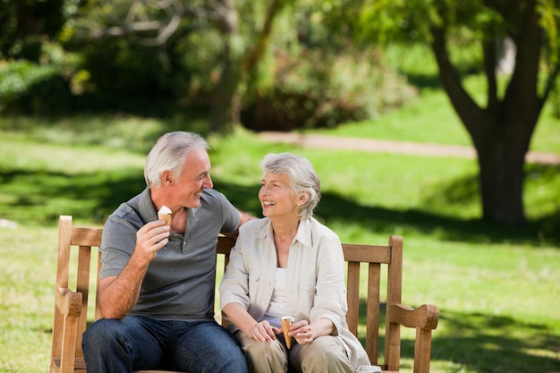 Senior pareja comiendo un helado en un banco