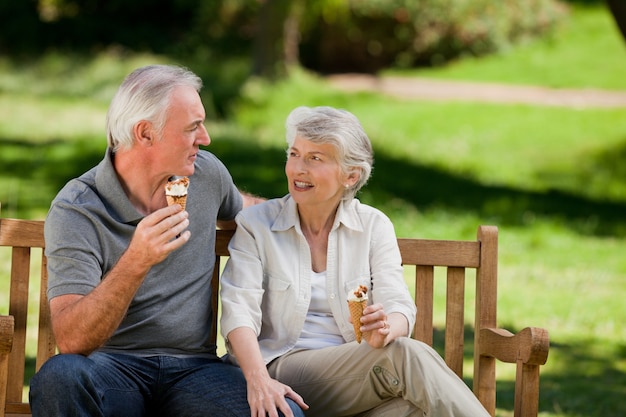 Senior pareja comiendo un helado en un banco