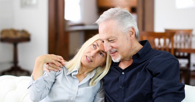 Senior pareja descansando en un sofá y hablando juntos