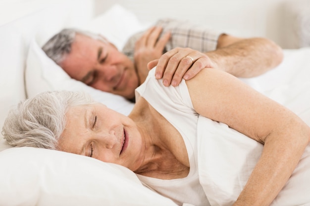 Senior pareja durmiendo en la cama en su casa