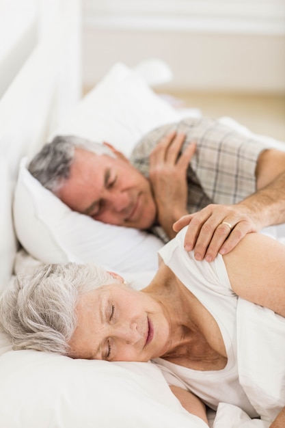 Senior pareja durmiendo en la cama en su casa