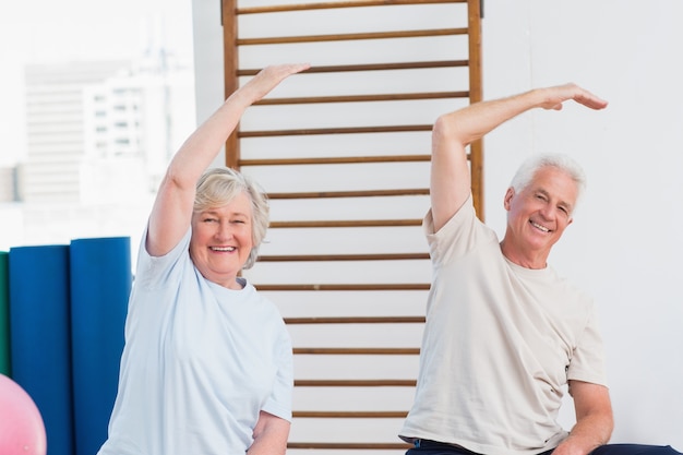 Senior pareja haciendo ejercicio de estiramiento en el gimnasio