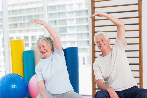 Senior pareja haciendo ejercicios de estiramiento en el gimnasio