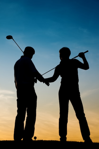 Senior pareja jugando al golf al atardecer