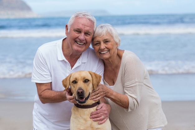 Senior pareja jugando con su perro en la playa