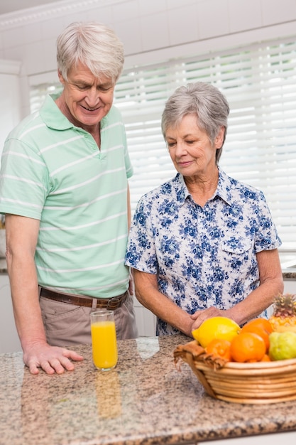 Senior pareja mirando el vaso de jugo de naranja