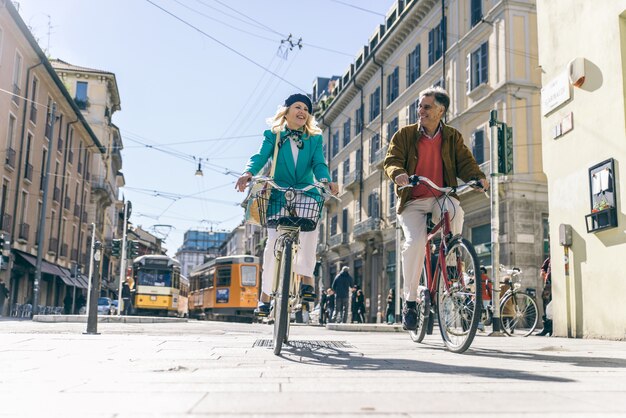 Senior pareja montando su bicicleta en el centro de la ciudad