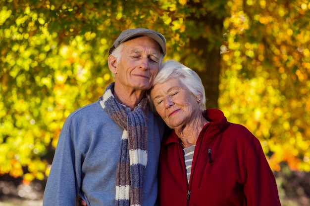 Senior pareja con los ojos cerrados en el parque durante el otoño