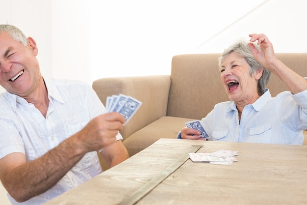 Senior pareja sentada en piso jugando a las cartas