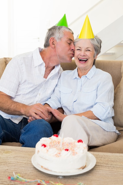 Senior pareja sentada en el sofá celebrando un cumpleaños