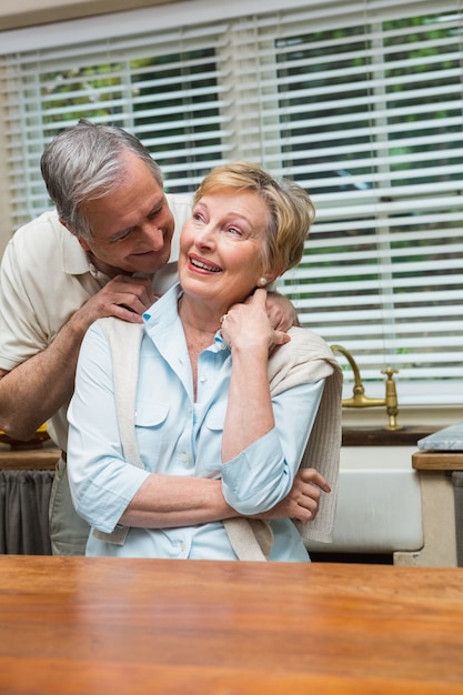 Senior pareja sonriendo a la cámara juntos en casa en la cocina