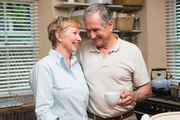 Senior pareja tomando un café juntos en casa en la cocina