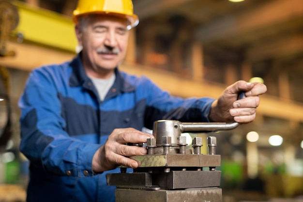 Senior professioneller Industriemaschinenservice-Arbeiter, der Griff des Eisengenerators während der Arbeit in der Fabrik dreht