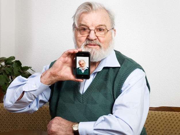 Senior sosteniendo un teléfono inteligente y mostrando su foto